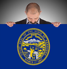 Image showing Smiling businessman holding a big card, flag of Nebraska