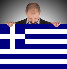 Image showing Smiling businessman holding a big card, flag of Greece