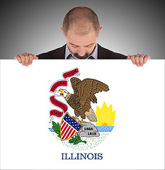 Image showing Smiling businessman holding a big card, flag of Illinois