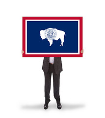 Image showing Smiling businessman holding a big card, flag of Wyoming