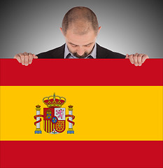 Image showing Smiling businessman holding a big card, flag of Spain