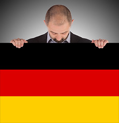 Image showing Smiling businessman holding a big card, flag of Germany