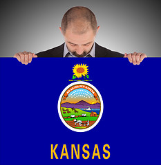 Image showing Smiling businessman holding a big card, flag of Kansas