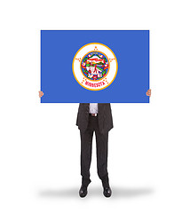 Image showing Smiling businessman holding a big card, flag of Minnesota