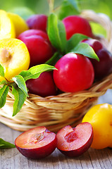 Image showing plums in basket and cut plum on table