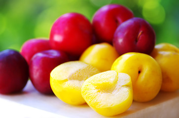 Image showing Ripe plums on wooden table and sliced plum