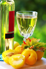 Image showing White wine bottle, glass and plums