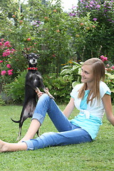 Image showing Cute little dog playing with a young girl