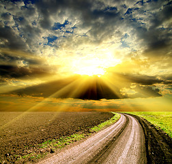 Image showing sun and clouds over field with road