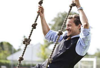 Image showing Happy businessman playing, swinging in ropes