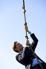 Image showing Businessman climbing rope