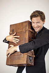 Image showing Young businessman embracing his old suitcase