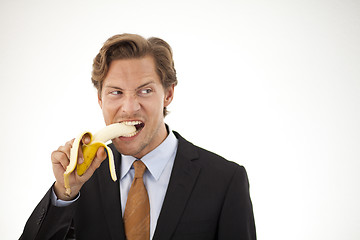 Image showing Suspicious businessman eating banana