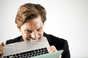 Image showing Man biting a laptop in frustration