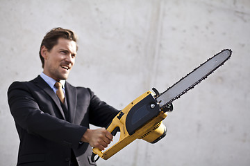 Image showing Angry businessman wielding a chainsaw.