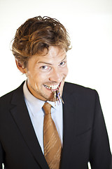 Image showing Smiling businessman holding keys between his teeth