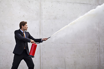 Image showing Focused businessman using a fire extinguisher