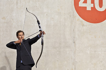 Image showing Businessman aiming bow and arrow at target