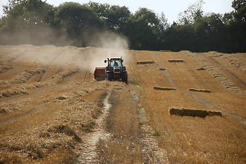 Image showing Tractor and baler in a field at harvest time