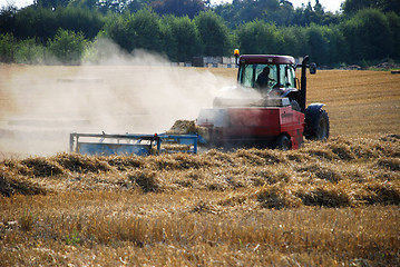 Image showing Tractor baling straw in a field