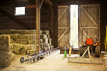 Image showing Barn interior with hay bales and farm equipment
