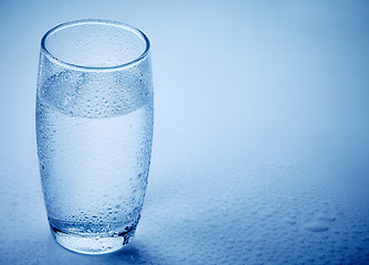 Image showing wet glass of water on blue background