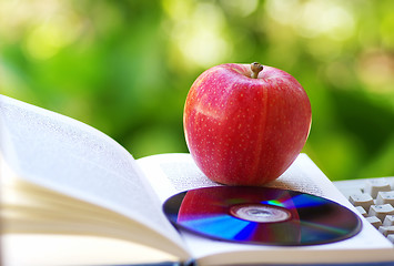 Image showing Ripe apple, dvd, and open book 