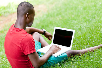 Image showing young smiling african student sitting in grass with notebook