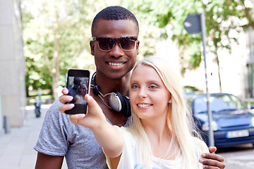 Image showing young smiling multiracial couple taking foto by smartphone 