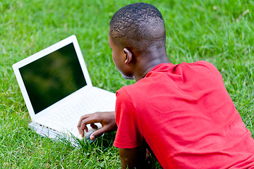 Image showing young smiling african student sitting in grass with notebook