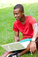 Image showing young smiling african student sitting in grass with notebook