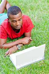 Image showing young smiling african student sitting in grass with notebook