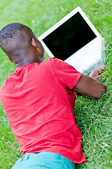 Image showing young smiling african student sitting in grass with notebook