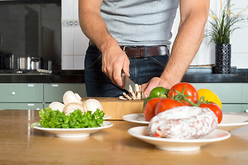 Image showing Midsection Of Man Cutting Vegetables At Kitchen Counter