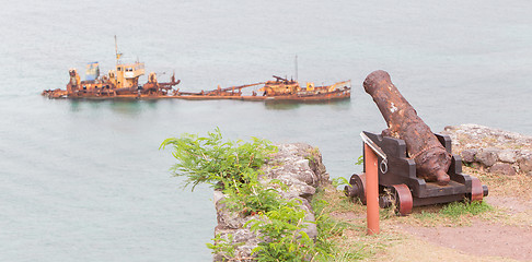 Image showing Old rusted canon pointing at a sunken ship, concept of humor