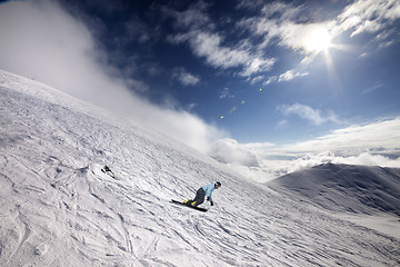 Image showing Snowboarder on off-piste ski slope and blue sky with sun