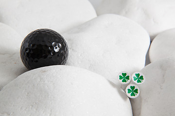 Image showing Black golf ball and four leaf clovers
