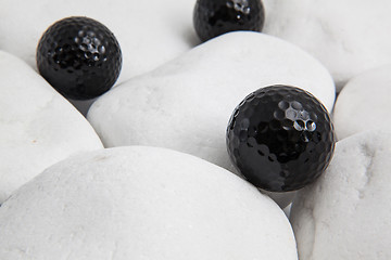 Image showing Black golf balls and white stones