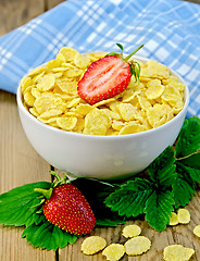 Image showing Corn flakes in bowl with strawberries on a board