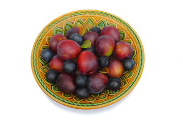 Image showing Ripe plums and prunes on ceramic dish on a white background.