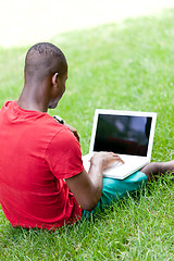 Image showing young smiling african student sitting in grass with notebook