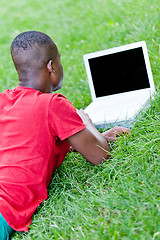 Image showing young smiling african student sitting in grass with notebook