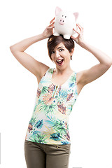 Image showing Woman holding a piggybank over her head