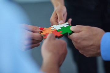 Image showing Group of business people assembling jigsaw puzzle