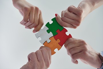 Image showing Group of business people assembling jigsaw puzzle