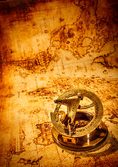 Image showing Vintage compass lies on an ancient world map.