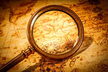 Image showing Vintage magnifying glass lies on an ancient world map