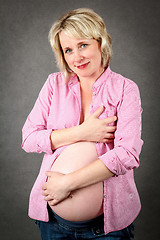 Image showing beautiful pregnant woman tenderly holding her tummy