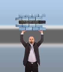 Image showing Businessman holding a large piece of a brick wall