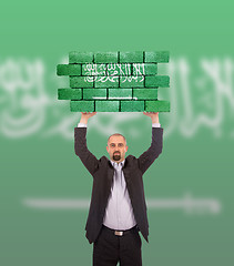 Image showing Businessman holding a large piece of a brick wall